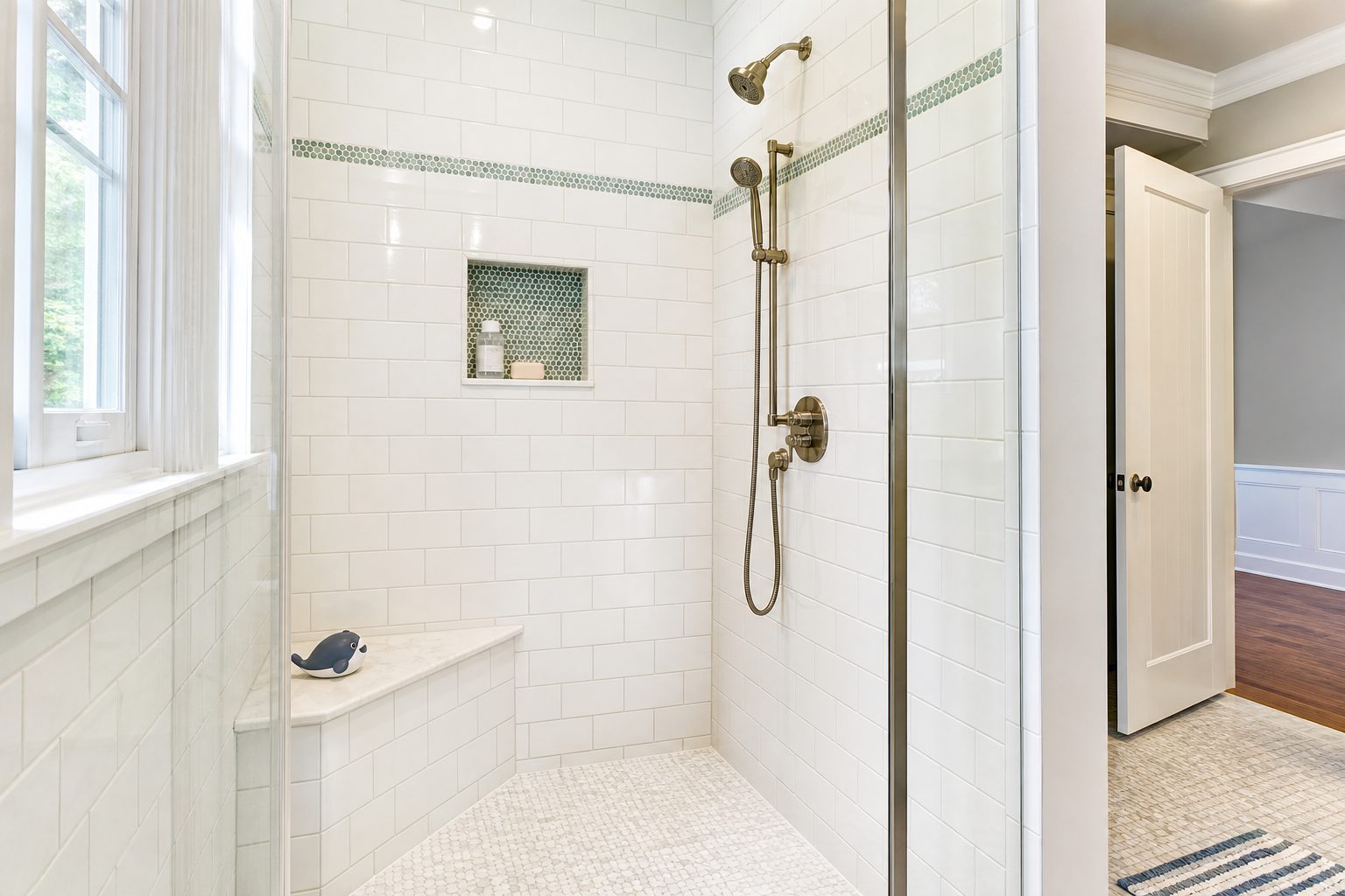 Family bathroom tile shower with built-in bench, niche, and non-slip mosaic floor in a Chester County PA home