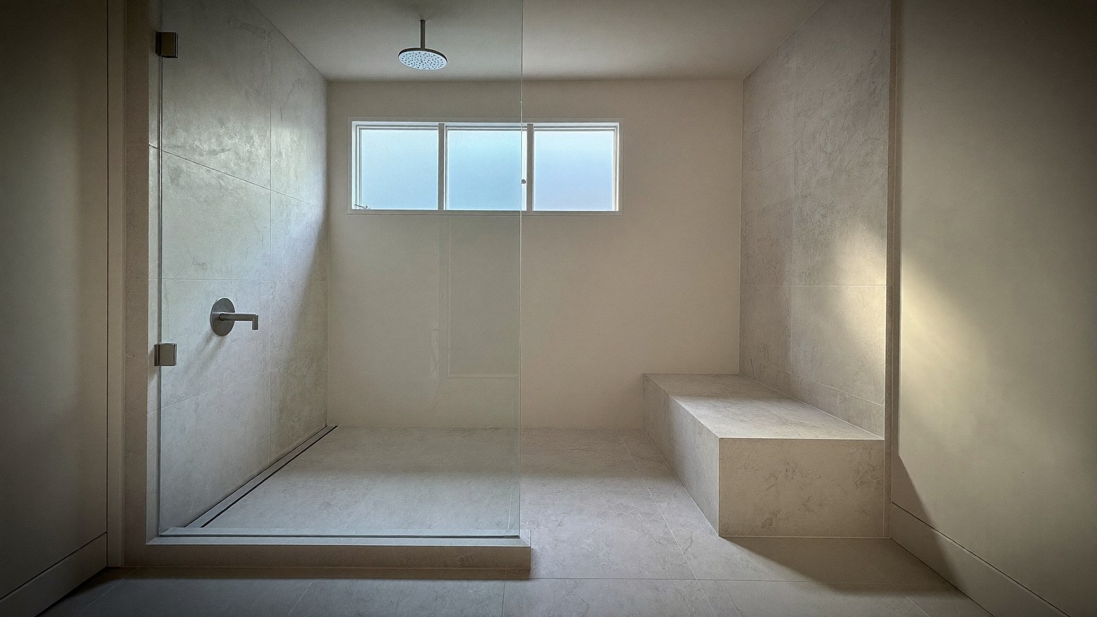 Curbless shower entry with a linear drain and tiled bench